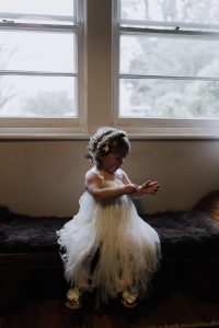 flower girl sitting by the window on the countryside wedding day