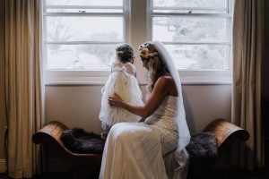 bride and flower girl sitting by the window on the countryside wedding day