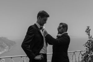 Grooms getting corsage pinned on to him by his best man at Palazzo Confalone, Ravello, Italy